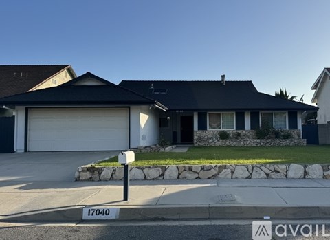 A house with a black roof and a garage door is numbered 17040.