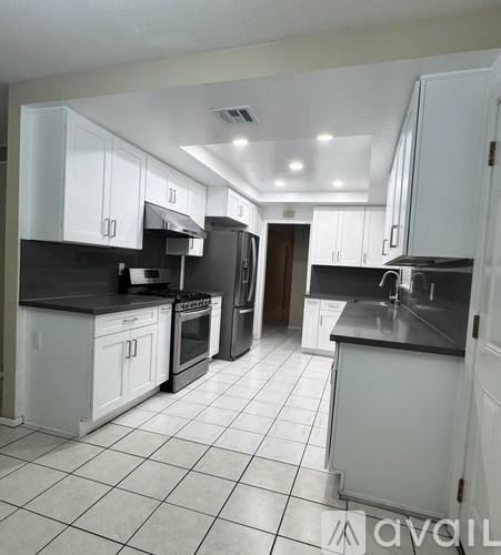 A kitchen with white cabinets and black countertops.