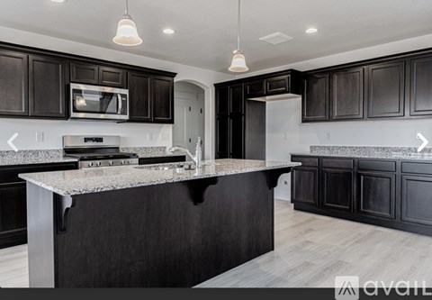 A modern kitchen with dark wood cabinets and a granite countertop.