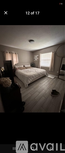 A bedroom with a bed, nightstand, and window.