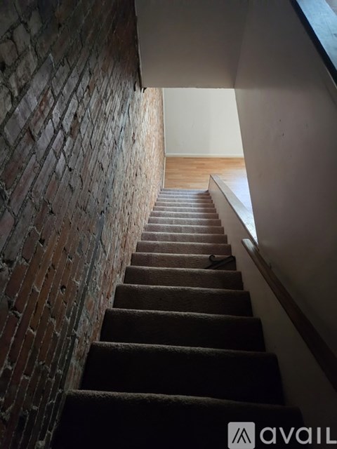A staircase with a brick wall on the left side.