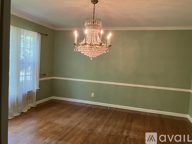 A room with a chandelier and a window with curtains.