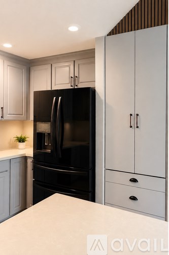 A black refrigerator in a kitchen with white cabinets.