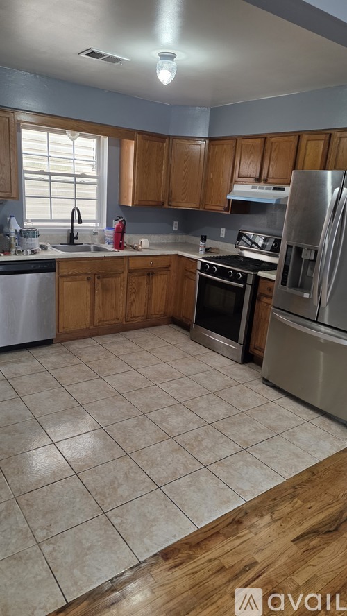 A kitchen with wooden cabinets and tile flooring.