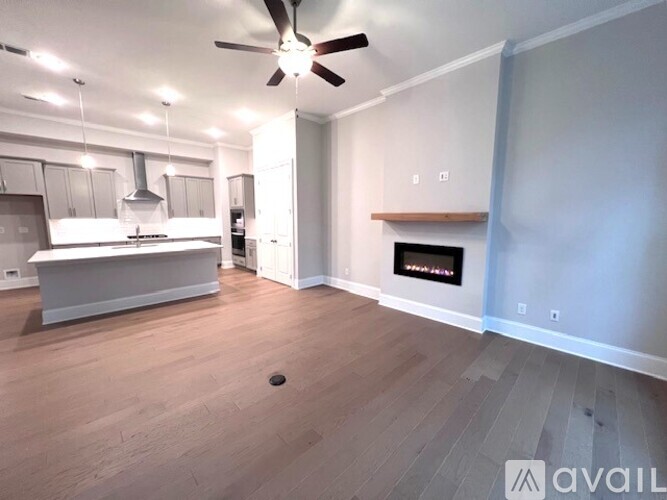 A spacious living room with a fireplace and a kitchen area in the background.
