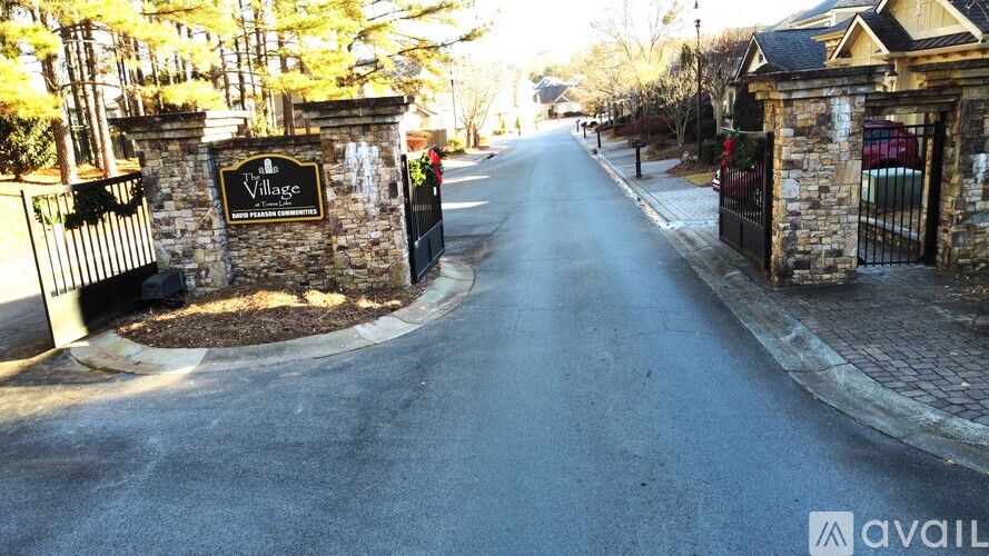A street view of a gated community entrance with the name "Village" on the sign.