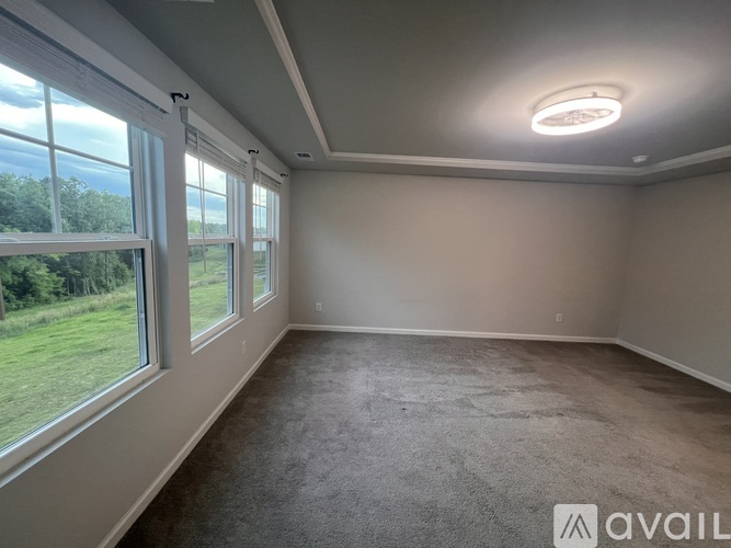A room with a carpeted floor and a large window overlooking a green field.