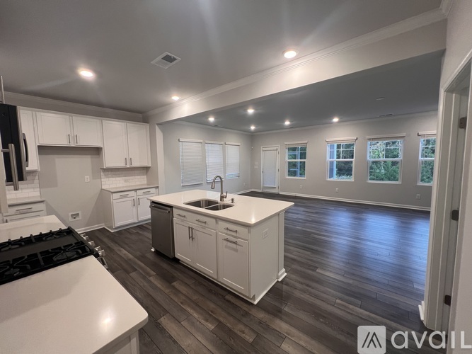 A modern kitchen with white cabinets and a wooden floor.