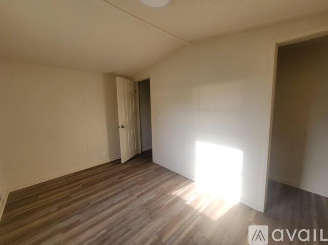 A room with wooden flooring and a door on the left side.