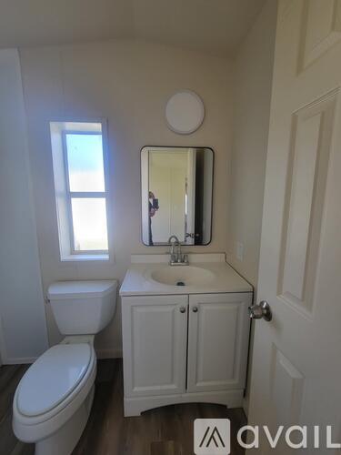 A white bathroom with a toilet, sink and mirror.