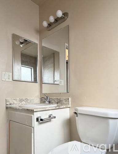 A bathroom with a white toilet, sink, and mirror.
