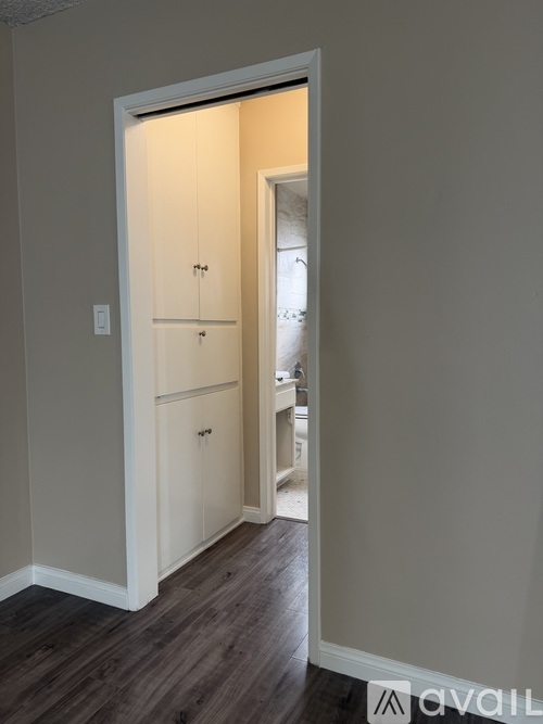 A white door with a cabinet on the left side and a small room visible through the door.