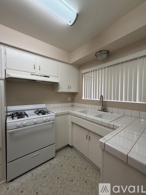 A kitchen with white cabinets and a white stove.