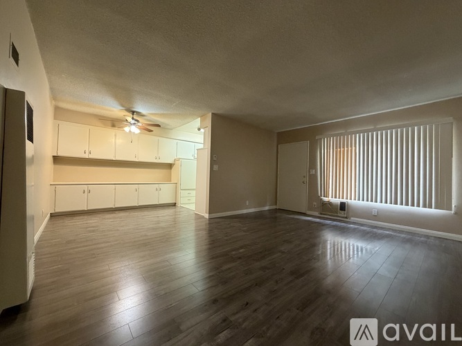 A spacious room with wooden flooring and a ceiling fan.