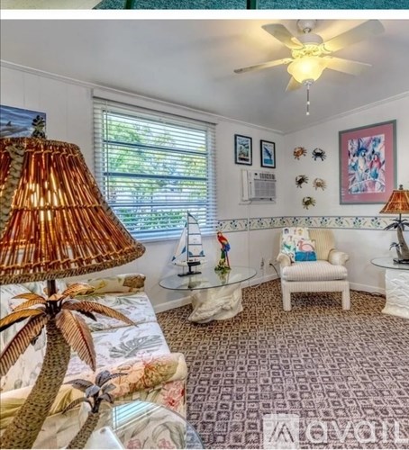 A living room with a palm tree lamp and a white chair.