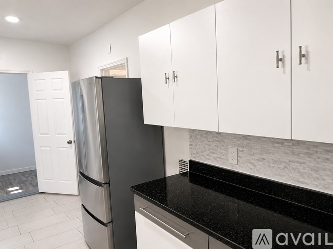 A kitchen with white cabinets and a black countertop.