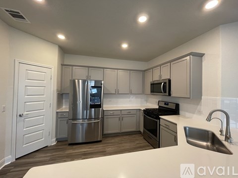A modern kitchen with stainless steel appliances and wooden flooring.
