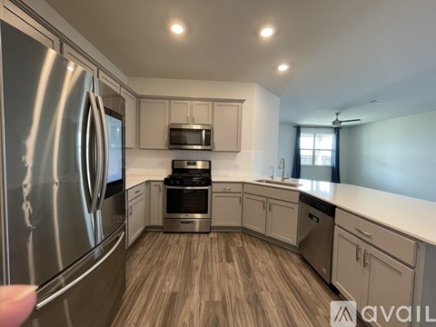 A modern kitchen with a stainless steel refrigerator and wooden flooring.