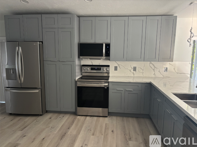 A kitchen with a refrigerator, oven, and microwave.