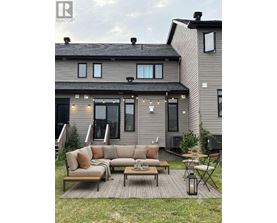 A modern house with a grey exterior and a patio with a couch, chairs, and a table.