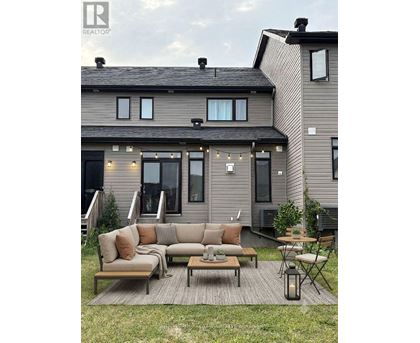 A modern house with a grey exterior and a patio with a couch, chairs, and a table.