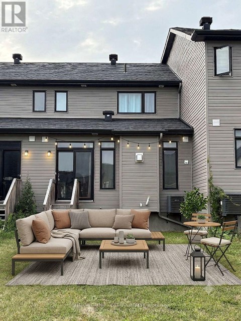 A modern house with a grey exterior and a patio with a couch, chairs, and a table.