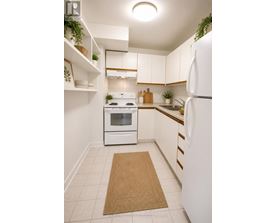 A white kitchen with a refrigerator, oven, and sink.