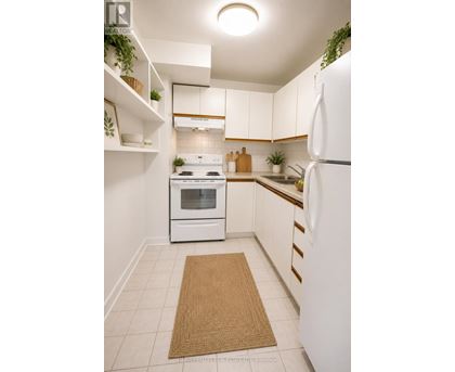A white kitchen with a refrigerator, oven, and sink.