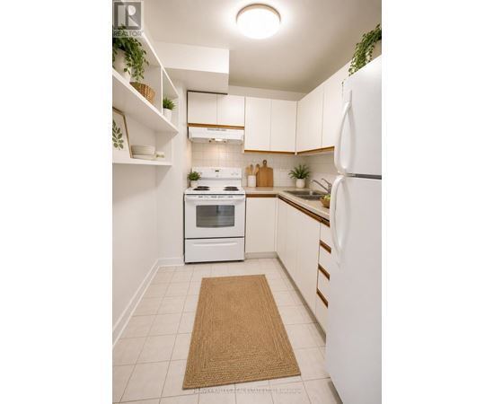 A white kitchen with a refrigerator, oven, and sink.