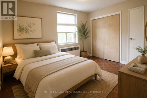 A bedroom with a large bed, a nightstand with a lamp, a window with a view of the sky, a plant, and a door.