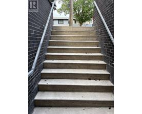 A set of concrete stairs with a metal railing on the side.