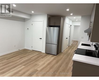 A kitchen with a refrigerator, sink, and cabinets.
