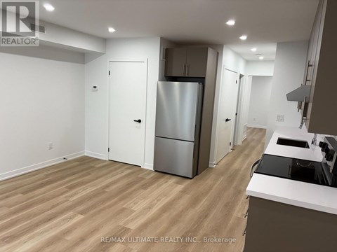 A kitchen with a refrigerator, sink, and cabinets.