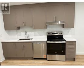 A modern kitchen with stainless steel appliances and beige cabinets.