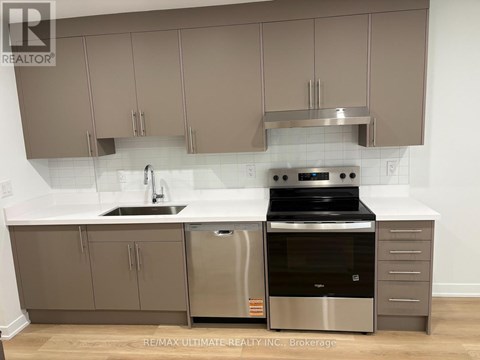 A modern kitchen with stainless steel appliances and beige cabinets.