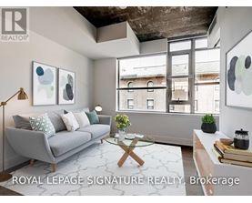 A living room with a grey couch, a glass coffee table, and a large window.