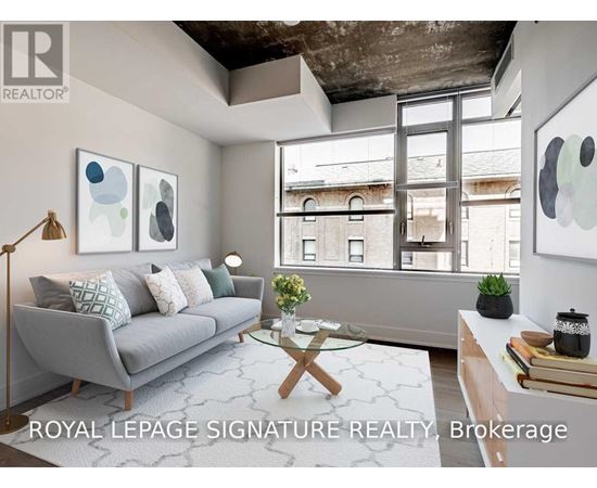 A living room with a grey couch, a glass coffee table, and a large window.