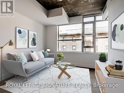 A living room with a grey couch, a glass coffee table, and a large window.
