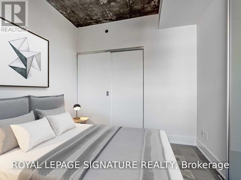 A bedroom with a bed, pillows, a lamp, and a painting on the wall.