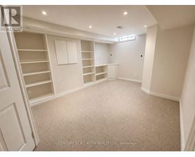 A spacious room with a staircase on the left and built-in shelves on the right.