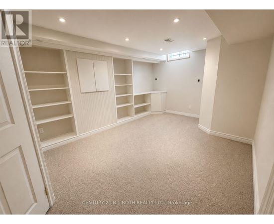 A spacious room with a staircase on the left and built-in shelves on the right.