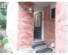 A red brick house with a black door and a small porch.