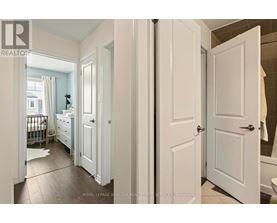 A white bedroom with a white door and a white dresser.