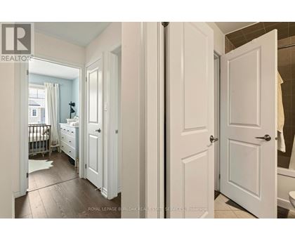 A white bedroom with a white door and a white dresser.