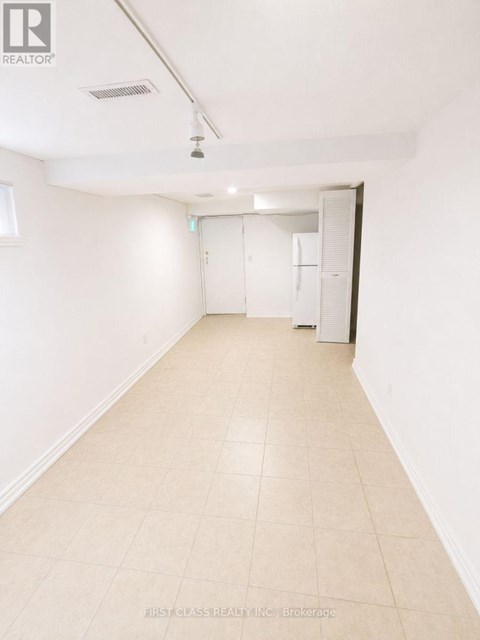 A long, empty hallway with white walls and tiled flooring.