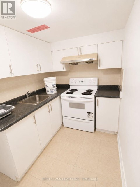 A small white kitchen with a stove and sink.