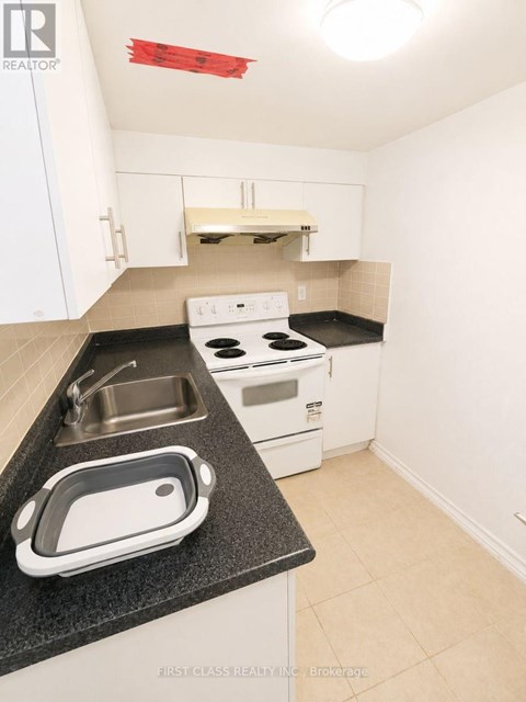 A kitchen with white cabinets and a black counter top.