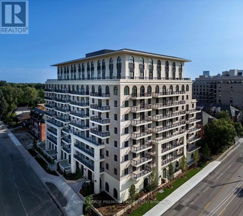 A large, multi-story building with balconies is situated on a street corner.