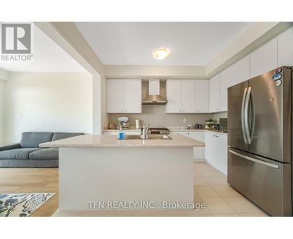A modern kitchen with a stainless steel refrigerator and a white island.