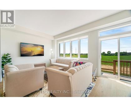 A living room with a large window and a painting on the wall.